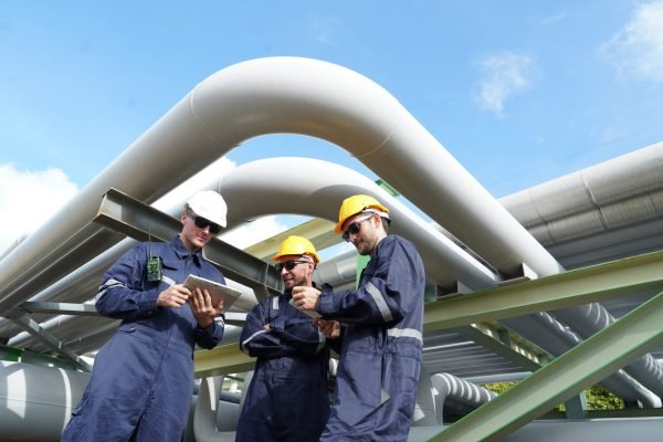 Male engineer in uniform holding tablet checking gas leakage pipe system and maintenance system and training oil refinery at column tank oil of Petrochemistry industry Male engineer in uniform holding tablet checking gas leakage pipe system and maintenance system and training oil refinery at column tank oil of Petrochemistry industry